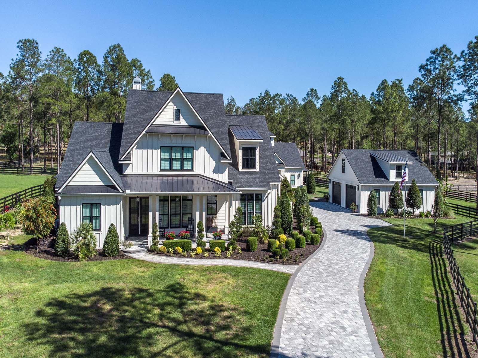 A white house with a black roof is sitting on top of a lush green field.