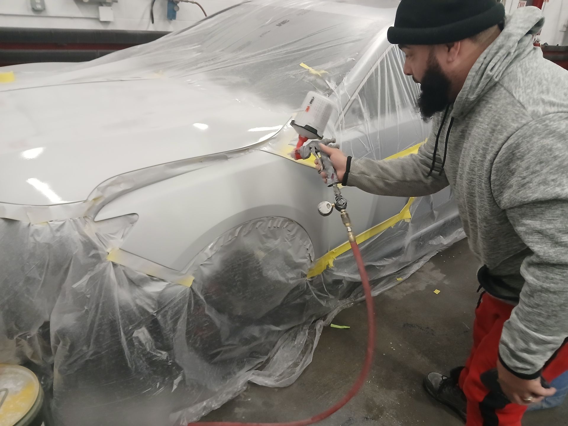A man is spray painting a car in a garage