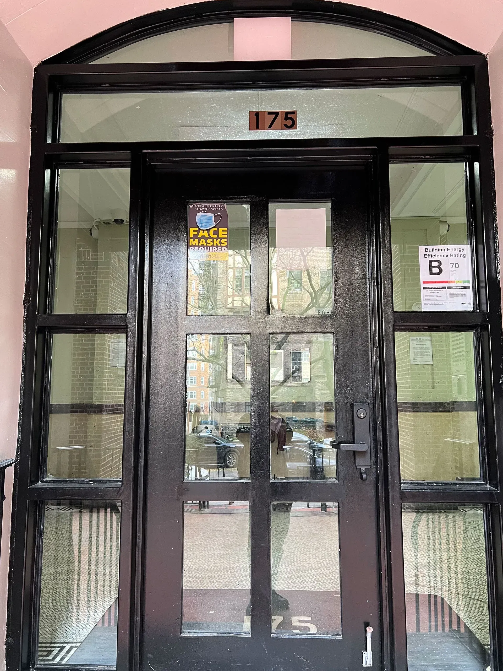 Black entrance door with glass panels and the number 175 above, set in pink trim.
