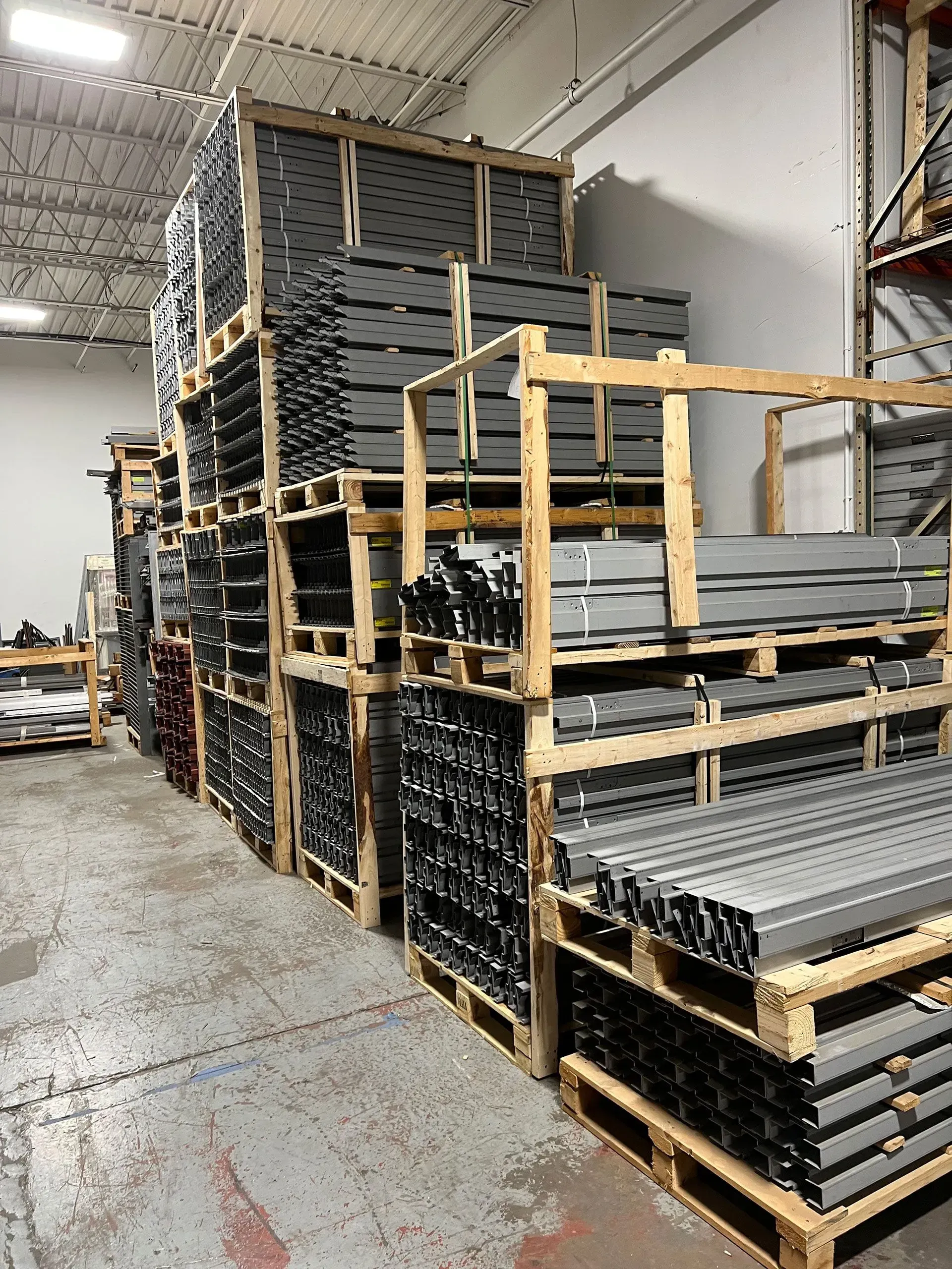 Stacks of metal beams on wooden pallets in a warehouse.