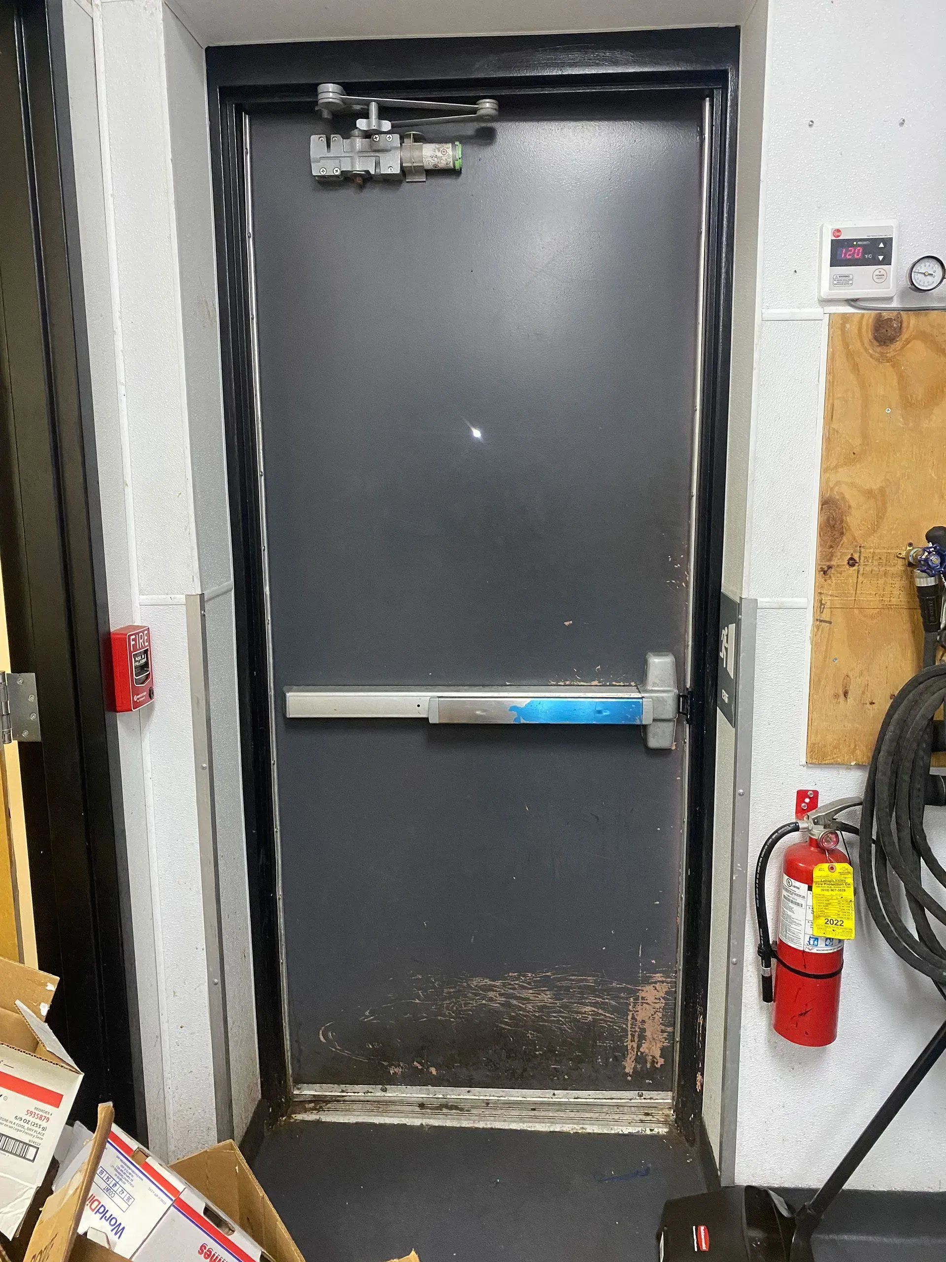 Metal door with push bar, emergency exit. Fire extinguisher on the right.