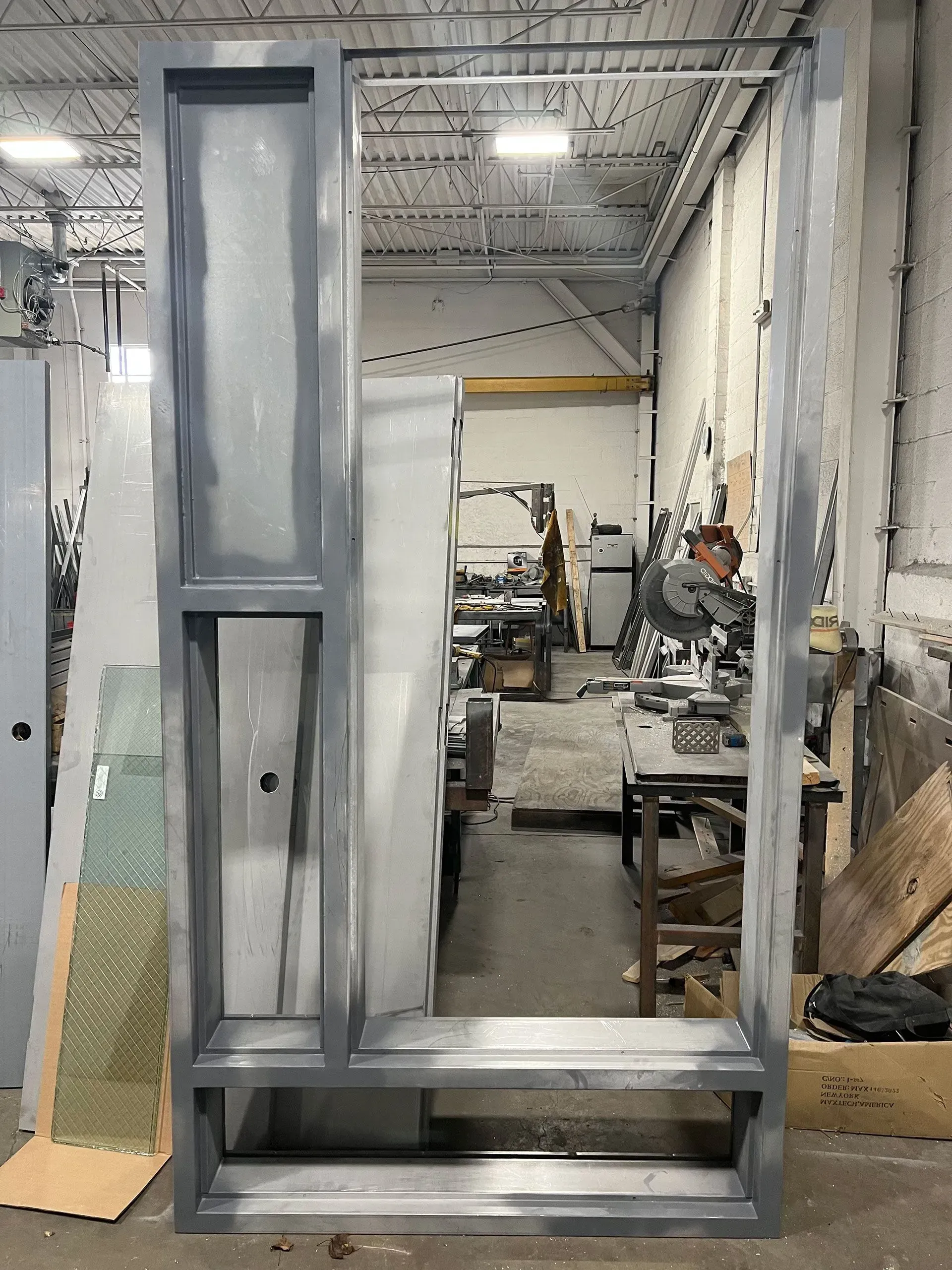 Gray metal frame of a window, with a workspace visible through the opening.