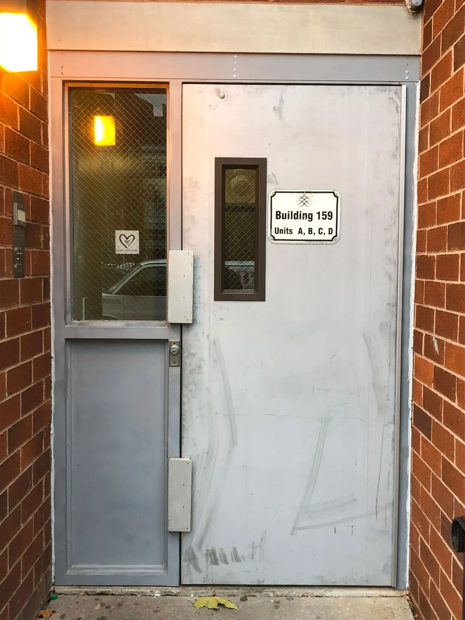 A gray metal door with a small window and a sign that says 