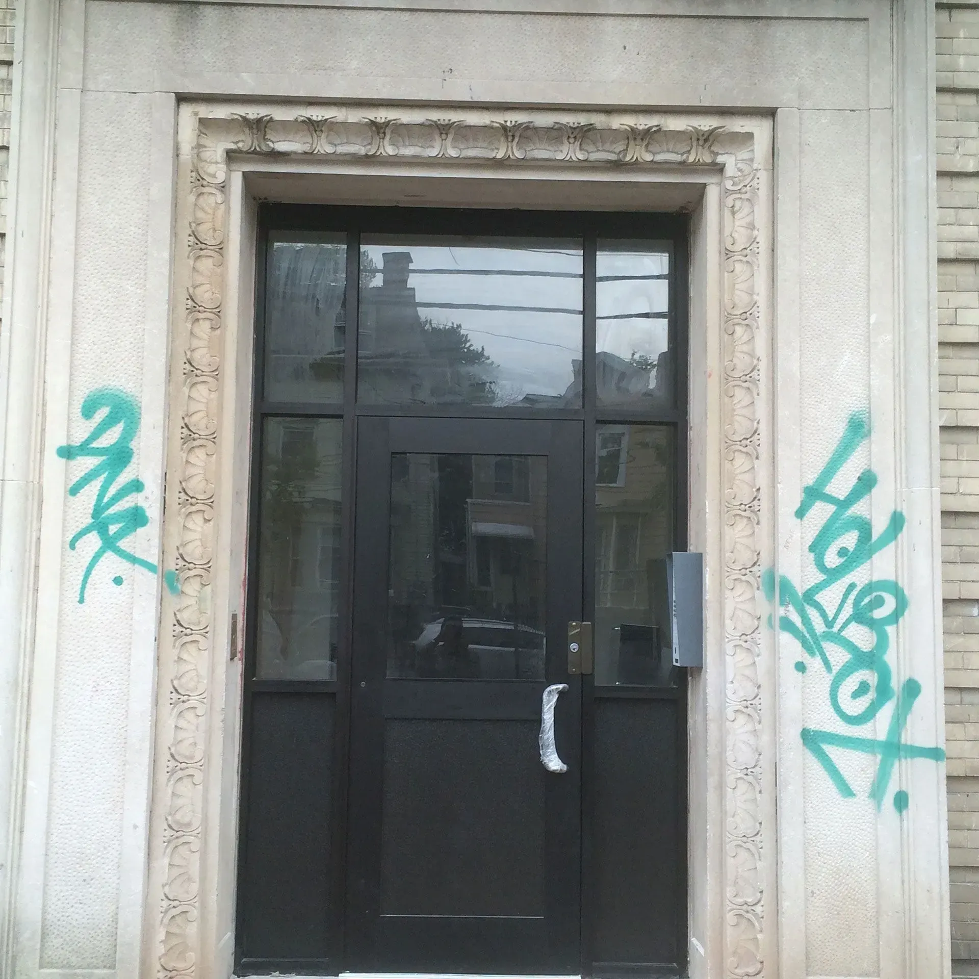 Black door in stone frame with green graffiti.