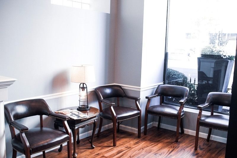 A waiting room with chairs and a table in front of a window.
