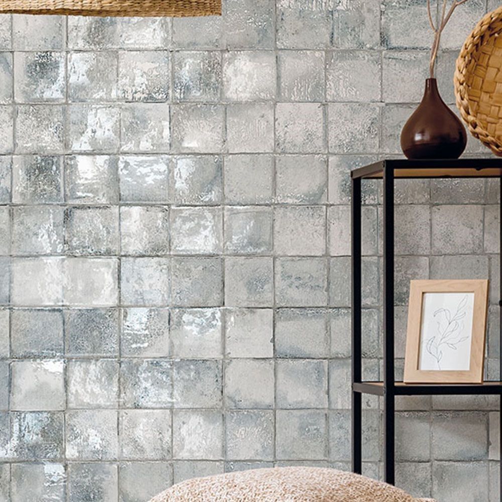 A picture frame sits on a shelf in front of a wall with square tiles