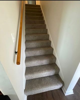 A staircase with a wooden railing and carpeted steps in a house.