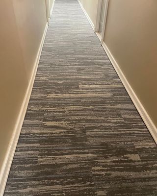 A long hallway with a carpeted floor and beige walls.