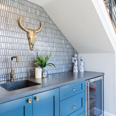 A kitchen with blue cabinets , a sink , and a bull skull on the wall.