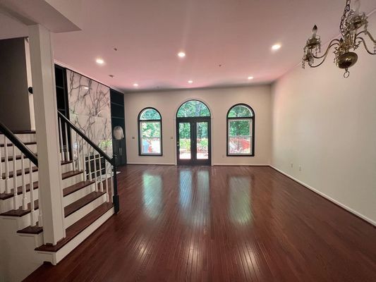 A large empty room with hardwood floors and stairs.
