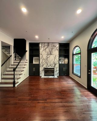 An empty living room with hardwood floors , a fireplace and stairs.
