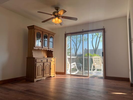 An empty living room with a ceiling fan and a sliding glass door.