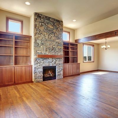 A living room with hardwood floors and a stone fireplace