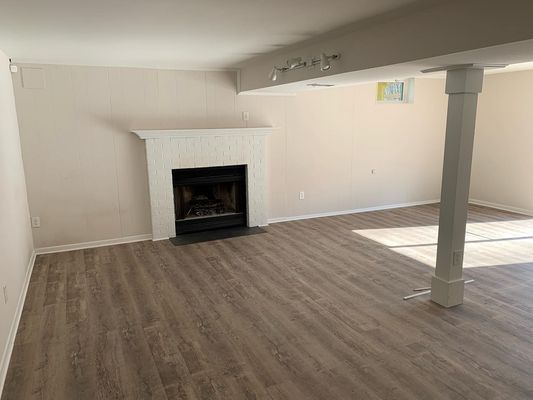 An empty living room with a fireplace and hardwood floors.