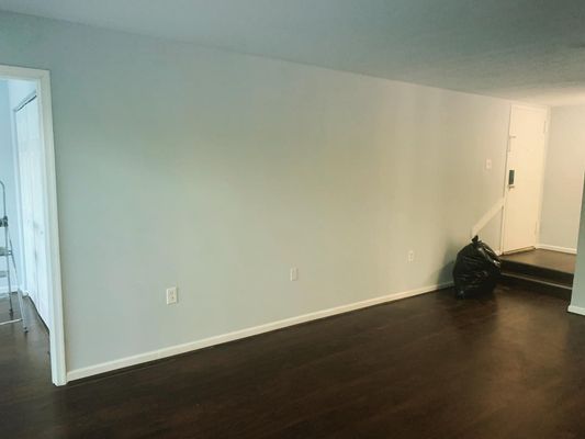 An empty living room with hardwood floors and white walls.