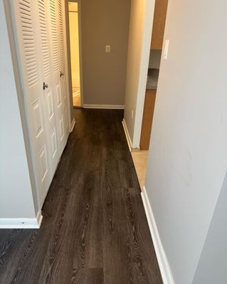 A hallway with hardwood floors and closets in a house.