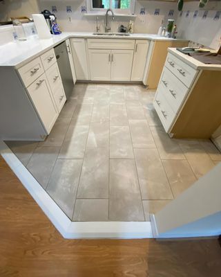 A kitchen with white cabinets and a tile floor.