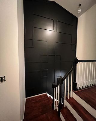 A staircase with a black wall and a white railing.