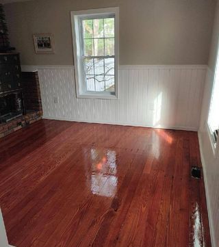 A living room with hardwood floors , a fireplace , and a window.