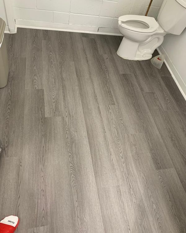 A bathroom with a toilet and a trash can on the floor.