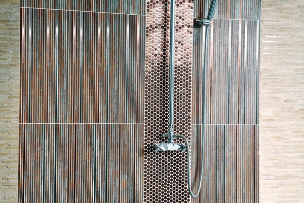 A shower head is hanging from a tiled wall in a bathroom.