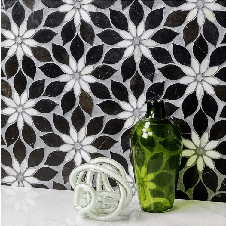 A green vase is sitting on a table in front of a black and white tile wall.