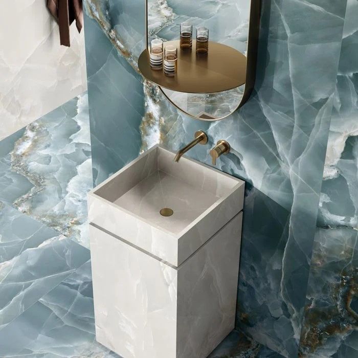 A kitchen sink with a faucet and blue tiles on the wall.