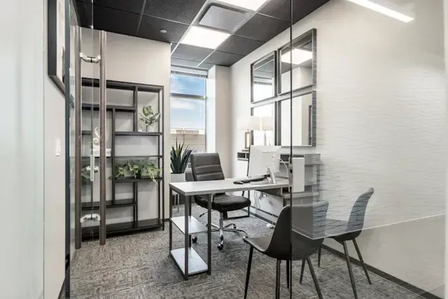 A small office with a desk, chairs, and a computer.
