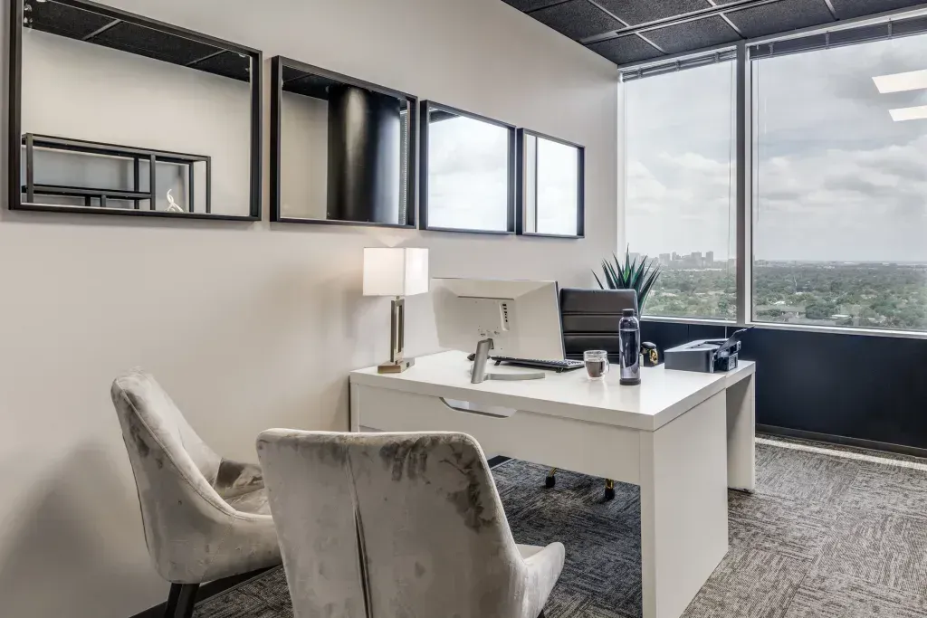 A large office with a desk, chairs, and a large window.