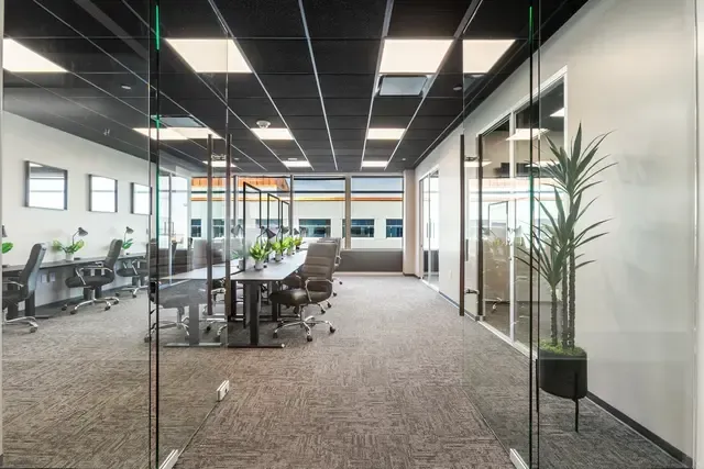 A large office with a lot of windows and tables and chairs.