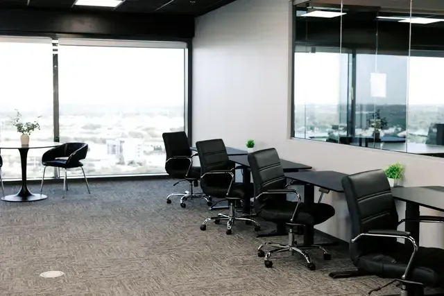 A room with tables and chairs and a large window.