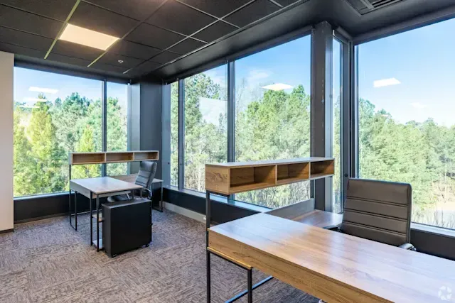 A small office with two desks and a chair in front of a large window.