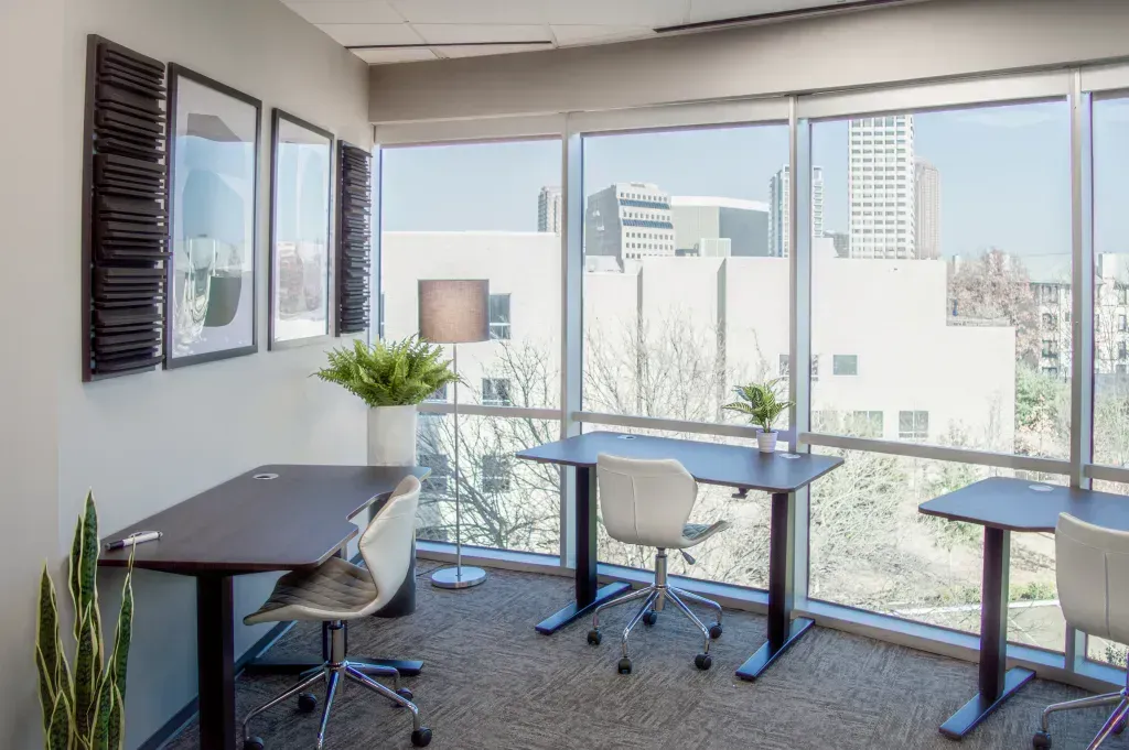 A room with three desks and chairs in front of a window.