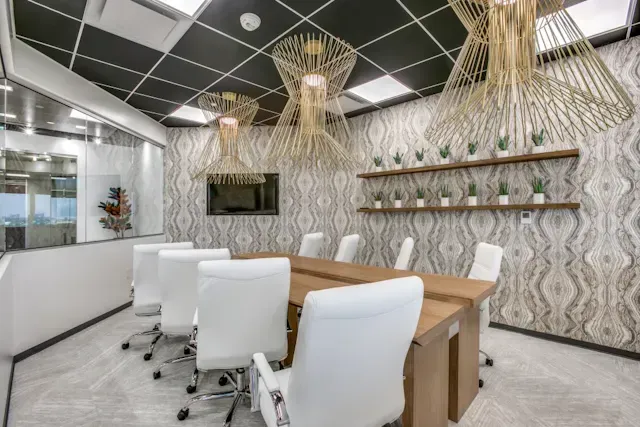 A conference room with a long wooden table and white chairs.
