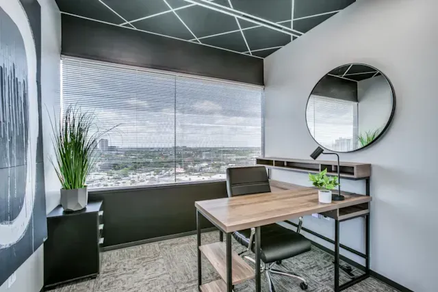 A small office with a desk and chair and a large window.