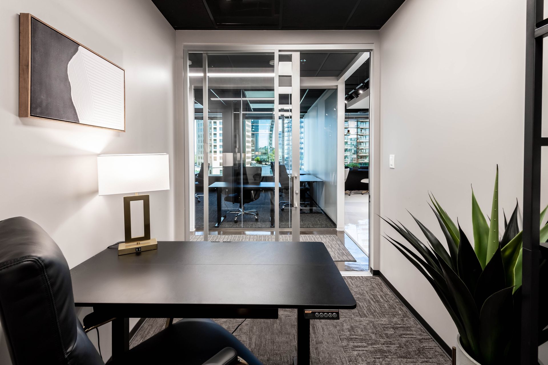 A small office with a desk, chair, and lamp.