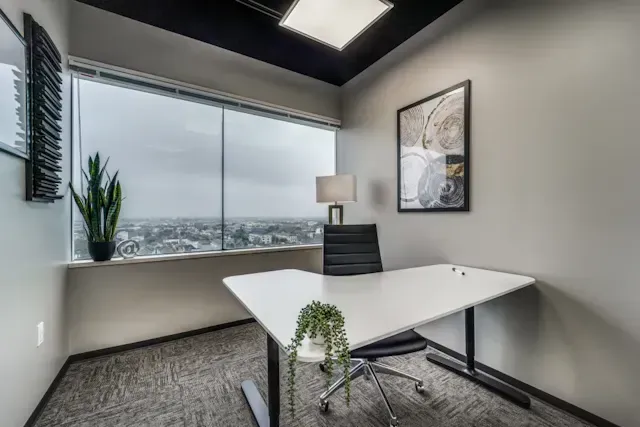 A small office with a desk and chair in front of a large window.