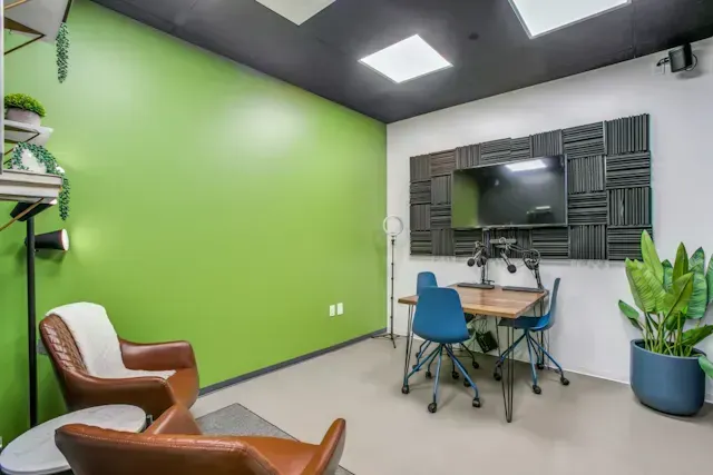 A conference room with green walls, chairs, a table, and a television.