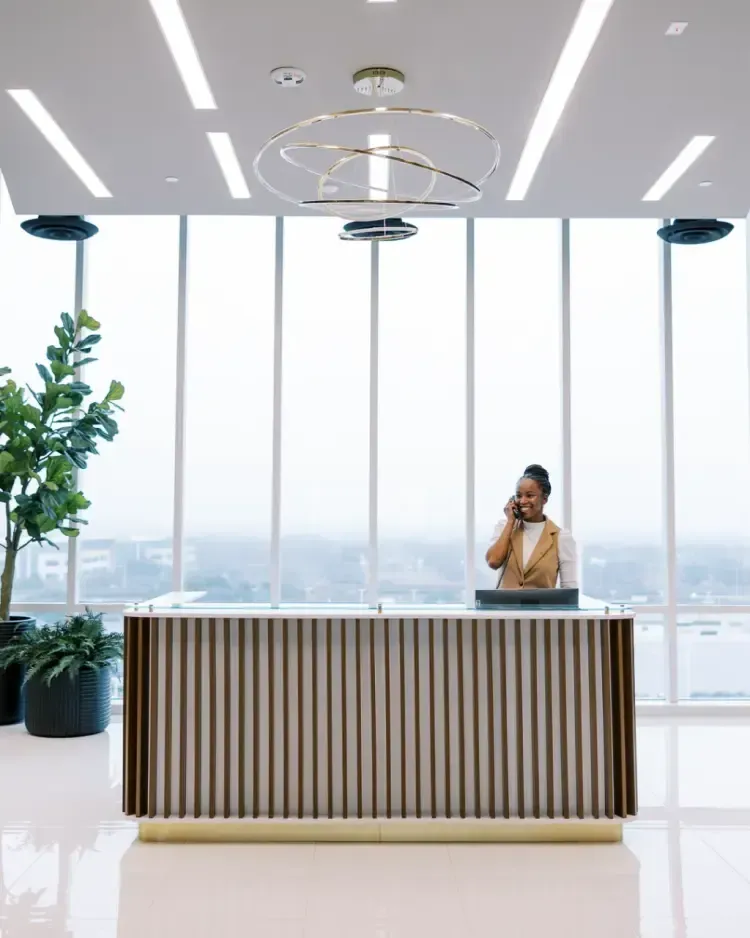 A woman is sitting at a reception desk talking on a cell phone.