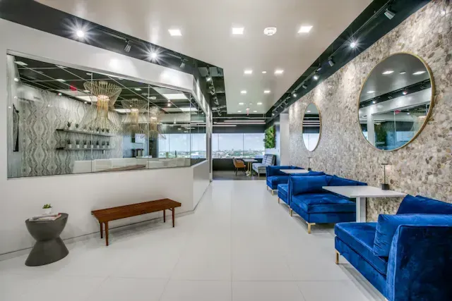 A large room with blue couches, tables, and mirrors.