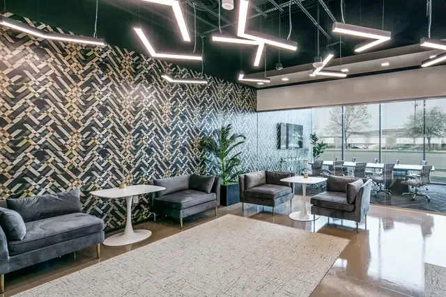 A living room with a couch, chairs, tables and a rug.