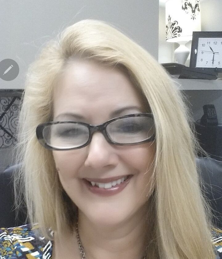 Smiling woman with blonde hair and glasses in an office setting