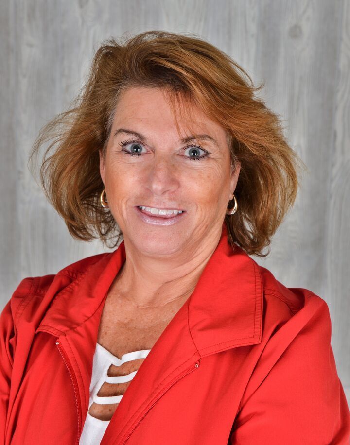 Portrait of a smiling woman in a bright red jacket against a gray backdrop