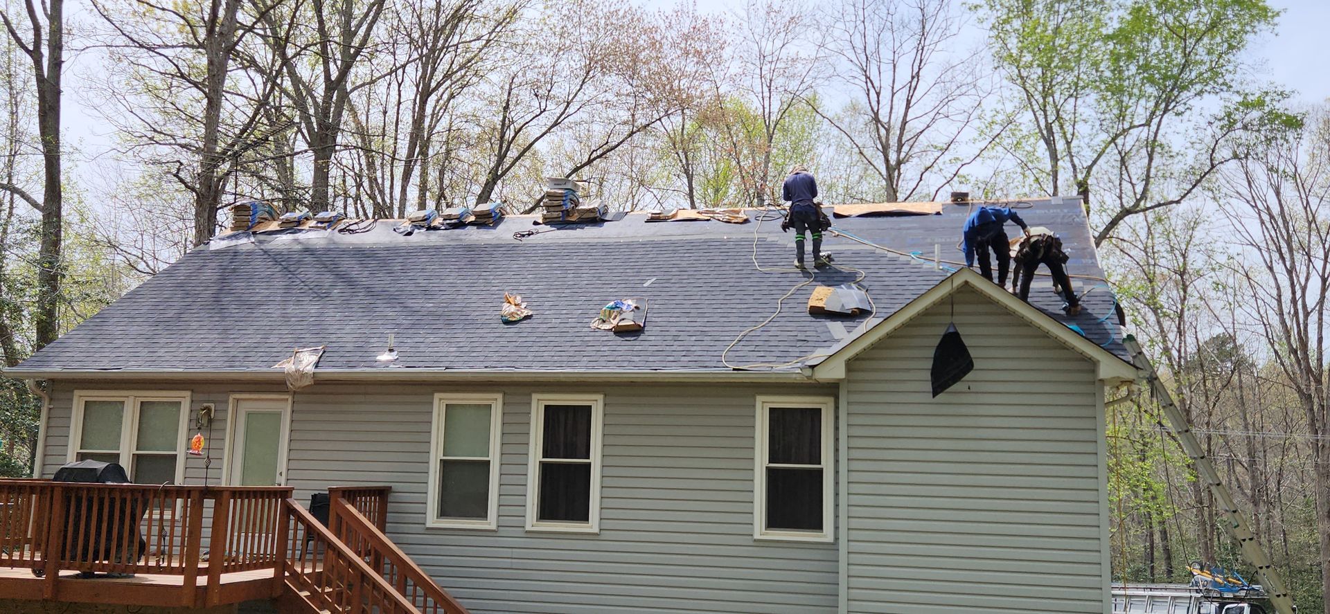 A group of people are working on the roof of a house.