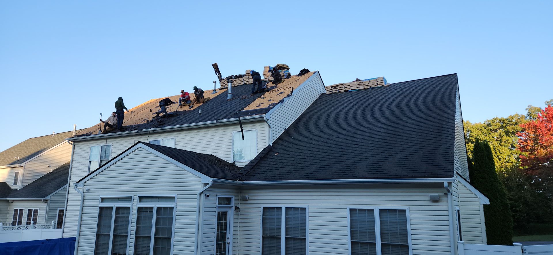 A group of people are working on the roof of a house.