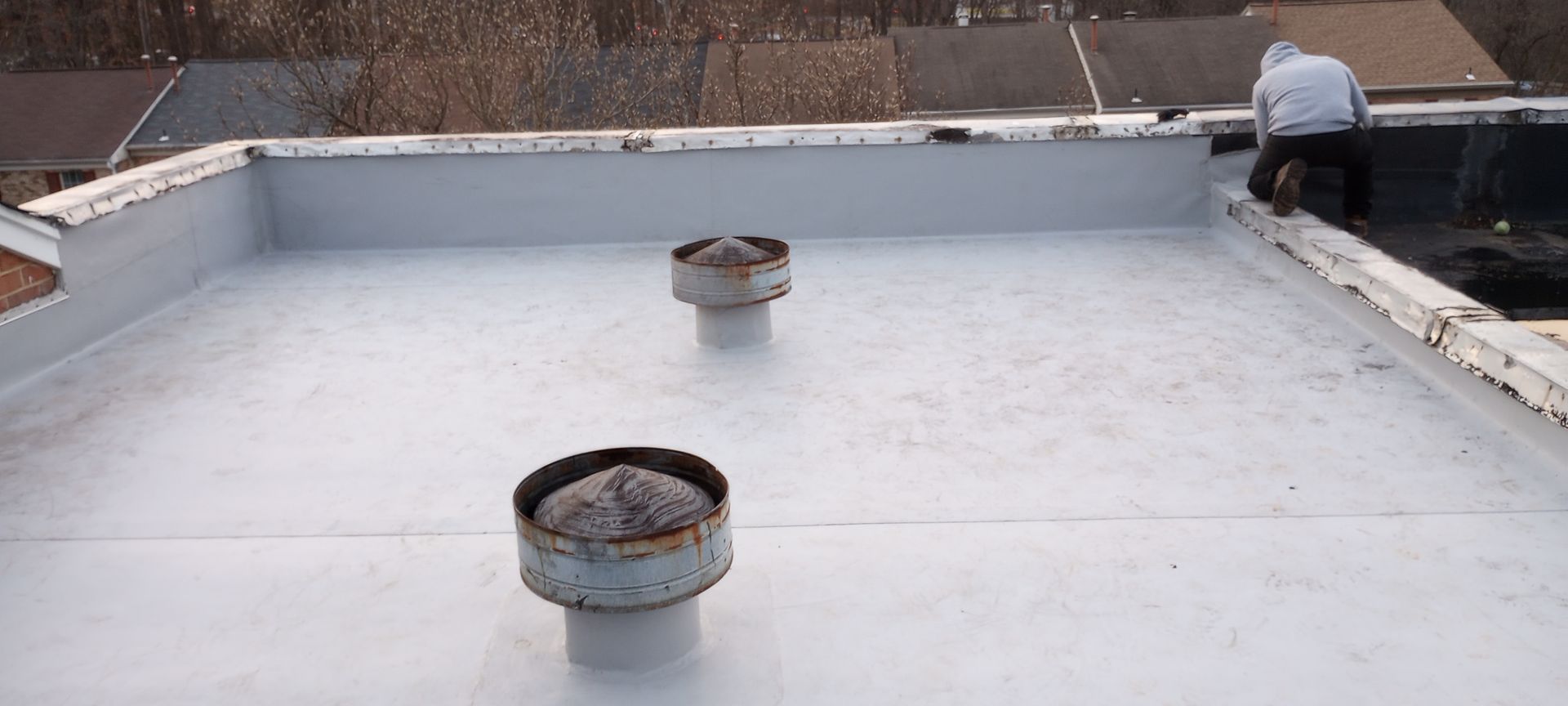 A man is sitting on top of a white roof.