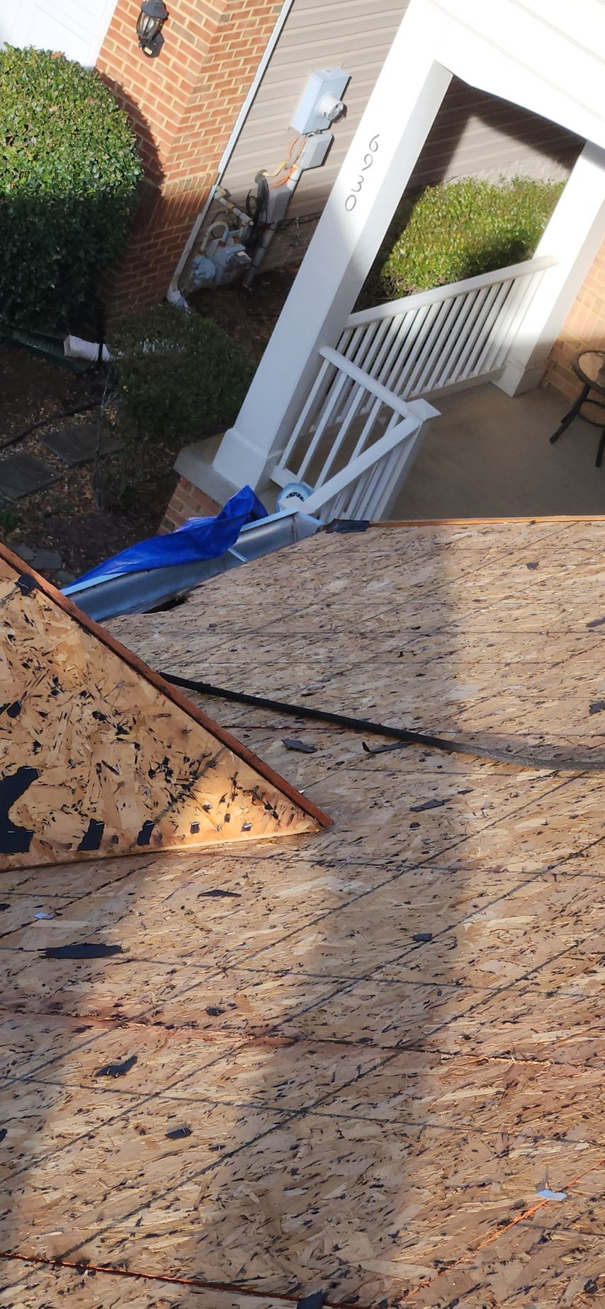 A piece of plywood is sitting on top of a roof next to a porch.