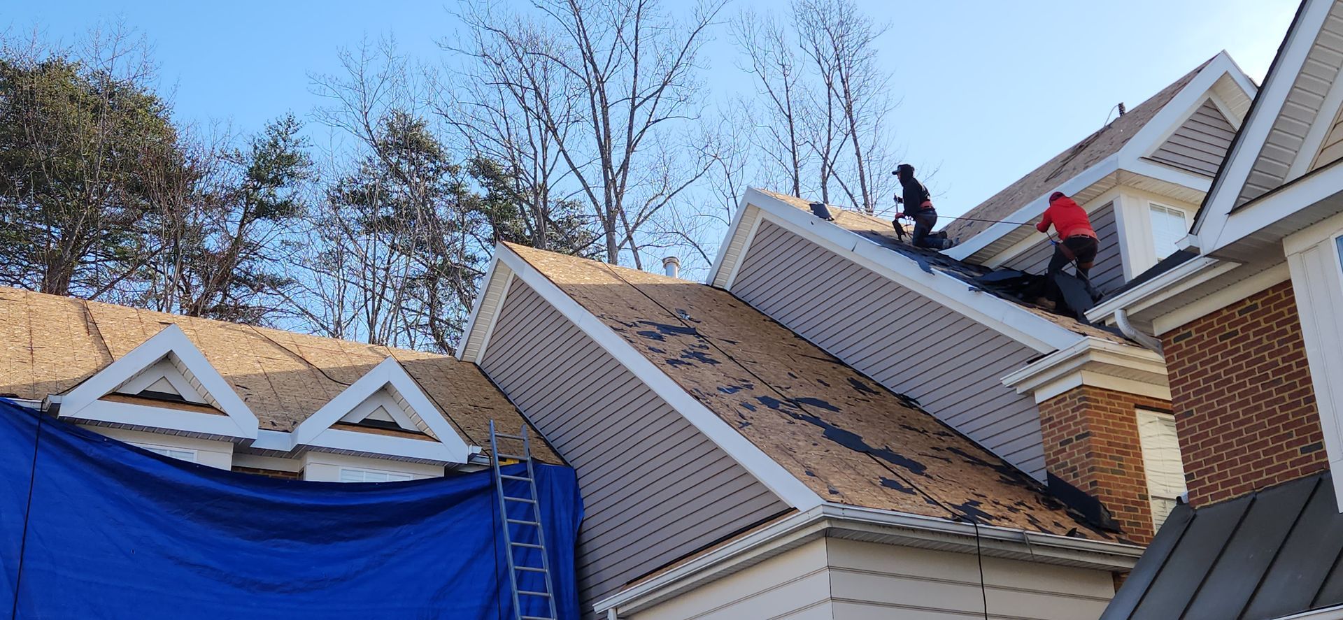 Two men are working on the roof of a house.