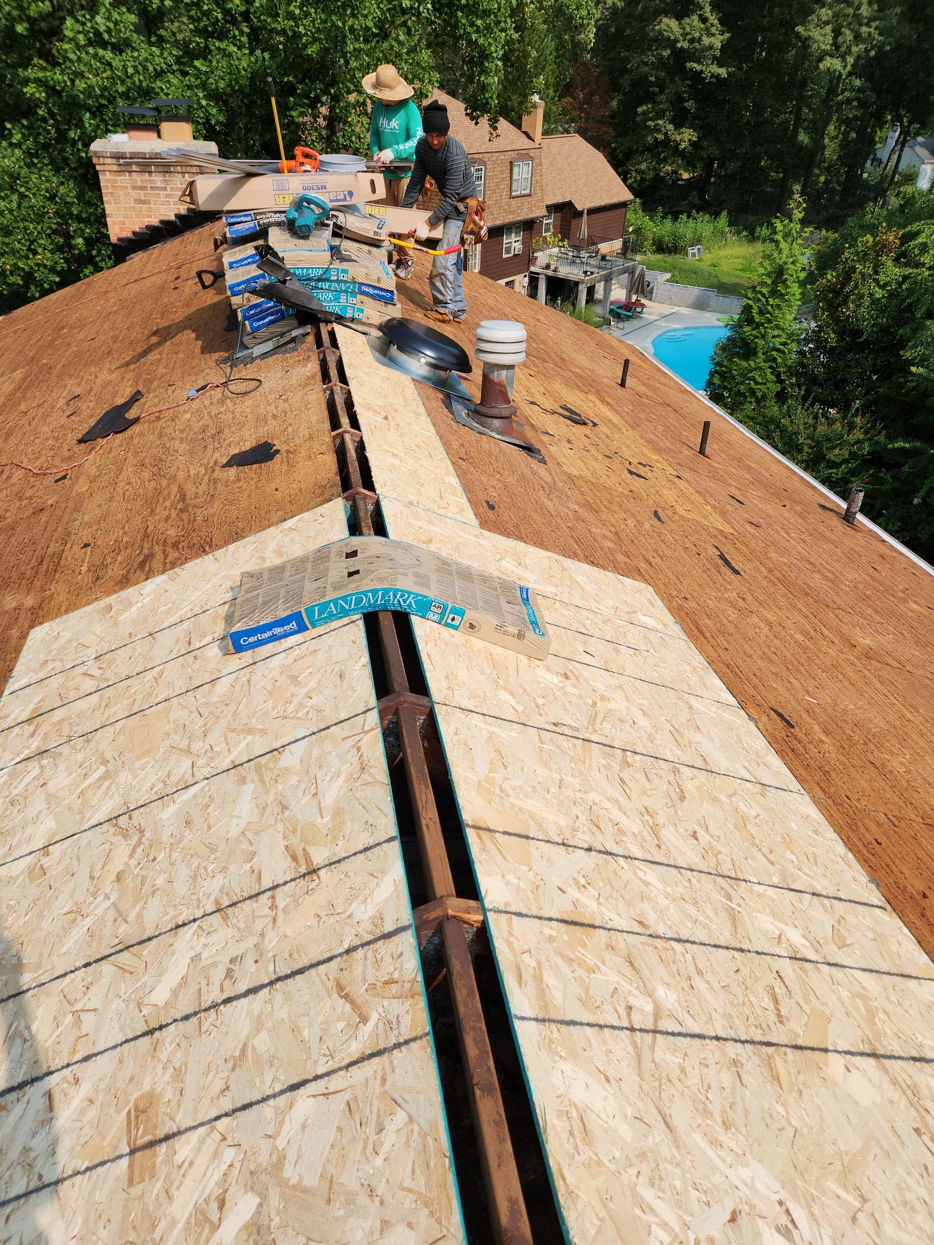 A roof is being built on top of a house with a pool in the background.