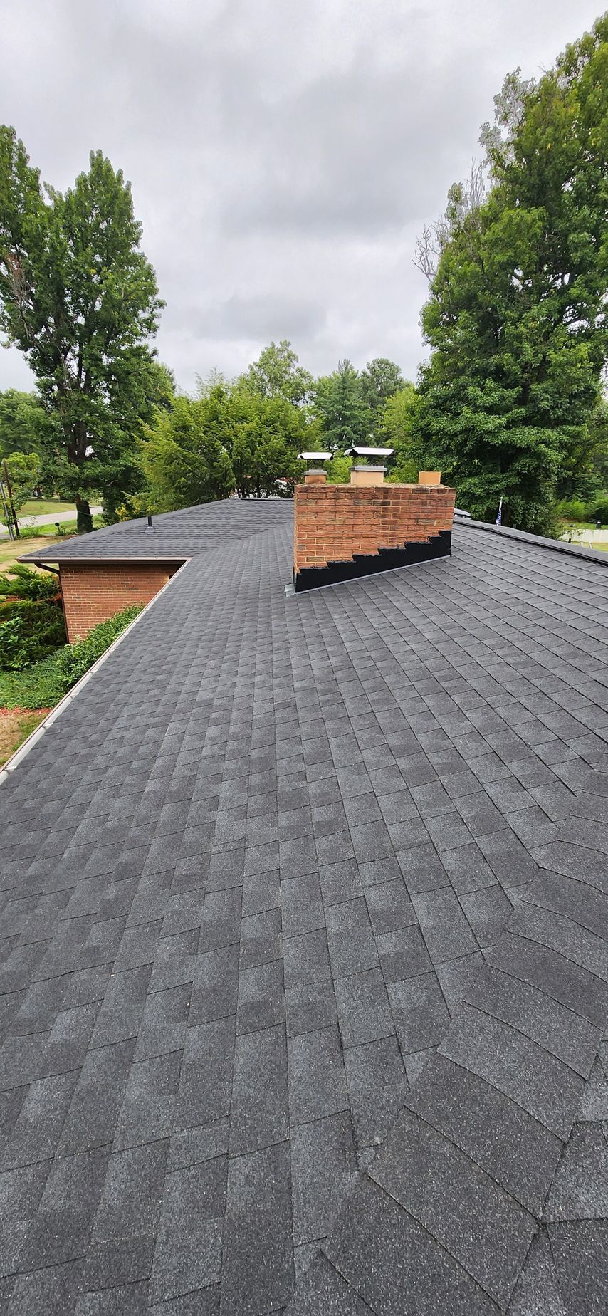 A roof with a chimney on top of it and trees in the background.